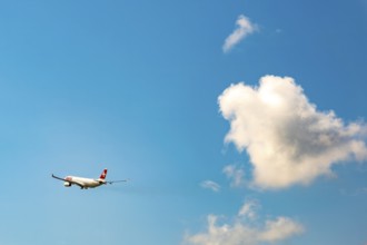 Swiss Airlines Passenger Airplane Flying Against Blue Sky and Clouds in a Sunny Summer Day From the