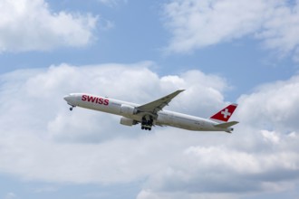 Swiss Airlines Passenger Airplane Flying Against Blue Sky and Clouds in a Sunny Summer Day From the