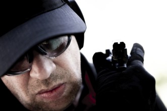 Face of a Man with Cap and Protection Eyeglasses Holding a Handgun Backward in Switzerland