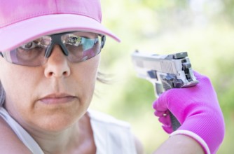 Portrait of a Woman with Cap and Protection Eyeglasses Holding a Handgun Backward in Switzerland