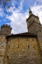 Clock Tower and Fortification Tower and Wall with Blue Sky and Clouds in a Sunny Autumn Day in City