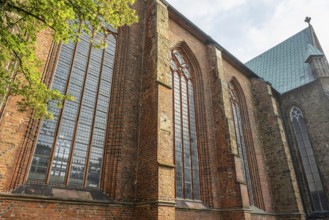 Gothic brick church with large stained glass windows and green trees in the foreground, Cathedral,