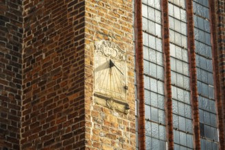 Sundial on a red brick wall next to large Gothic windows, cathedral, Verden an der Aller, Lower