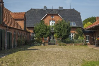An idyllic brick farmhouse with trees and a cobbled courtyard under a sunny sky, Oiste, Blender,