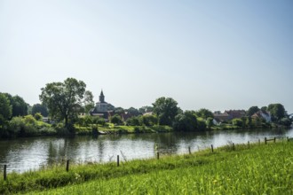 Rural view of a village with a church by the river, surrounded by green nature and a peaceful