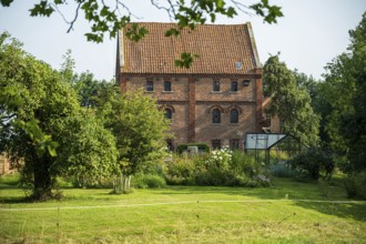 A large brick building with garden, surrounded by trees and vegetation on a summer's day, Bücken,
