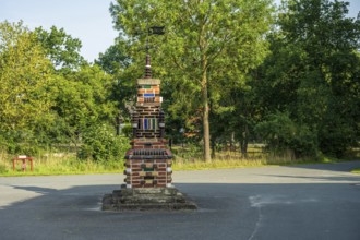 Colourful brick sculpture in a park with green trees in the background in the afternoon, Bücken,