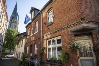 Brick houses with church in the background, surroundings full of plants and flags, Warendorf,