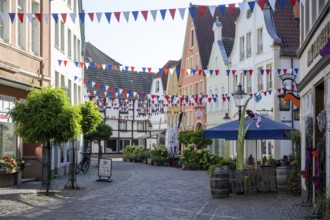 Colourfully decorated street in an old town with garlands and plants along the pavements,