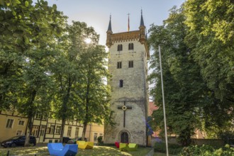 Tower in the town park with colourful chairs and flag, surrounded by tall trees, tower of the old