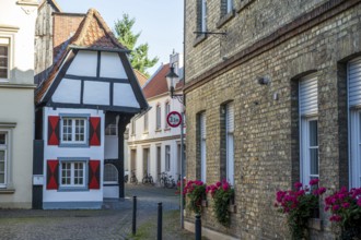 Small half-timbered house in narrow street decorated with flowers, historic surroundings,