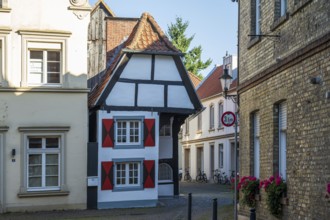 Small half-timbered house in a narrow lane, decorated with eye-catching red shutters, Warendorf,