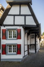 Detailed view of a half-timbered house with striking, colourful shutters on cobblestones,