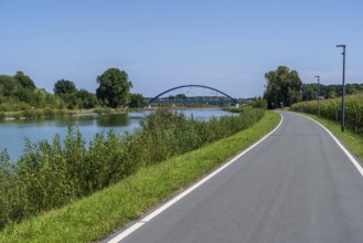 Cycle path along a river with a view of a bridge and green landscape, Dortmund-Ems Canal near