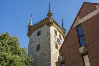 Old tower next to a modern building, in a clear blue sky, tower of the old St Mary's Church,