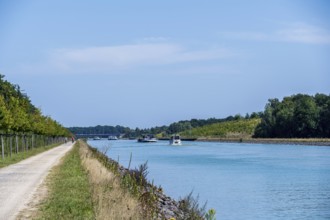 Canal with boats and clear sky. Calm water surrounded by nature and a gravel path, Dortmund-Ems