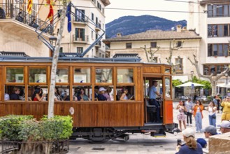 Vintage tramcar passing through town square in the centre of Sóller with tourists, Soller,