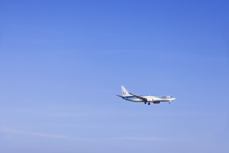 Passenger plane with tourists from the travel company Tui flying on a clear blue sky, Mallorca,