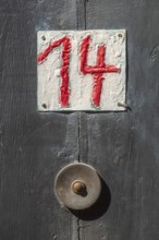 House number sign number fourteen and old doorbell on a half-timbered house in the old town centre,