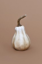 Single ceramic pumpkin ornament on brown background. Minimal autumn decoration object