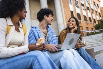 Group of diverse university students sharing a happy moment, laughing and eating lunch together on