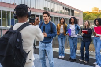 Student journalist filming and interviewing a young male student while a diverse group of female