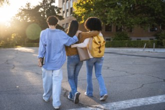 Diverse group of female students with arms around each other walking on a university campus at