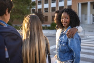 Diverse group of young students smiling and walking on a university campus during sunset,