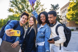 Happy diverse university friends smiling and taking a campus selfie with a smartphone, enjoying