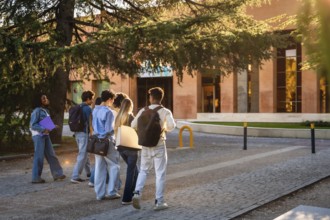 Group of diverse university students with backpacks and folders walking together on campus, heading
