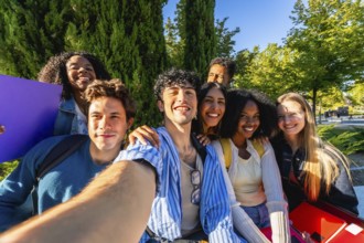 Diverse group of happy young adult students smiling while taking a group selfie together on