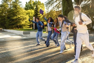 Group of excited multiracial students. Wearing casual clothes and carrying backpacks and books.