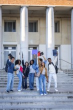 Diverse group of happy college students standing on the outdoor stairs of a university building,