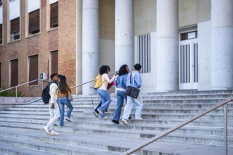 Diverse group of college students walking up wide outdoor steps toward a university building with