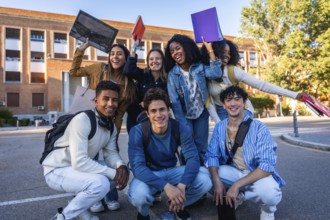 Diverse group of smiling university students on campus holding folders and backpacks, enjoying