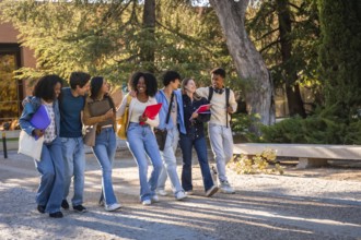 Group of multicultural university students walking and talking cheerfully together, carrying books,