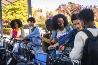 Group of happy diverse university students activating a shared bicycle from a station, preparing to