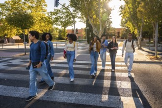 Group of multi ethnic university students walking together across a crosswalk on a sunny day,