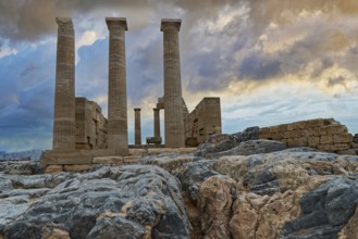 Ancient columns of the Temple of Athena on the Acropolis of Lindos in front of a dramatic sky and