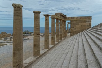 Ancient columns of the Acropolis of Lindos with a view of the sea and a staircase under a cloudy