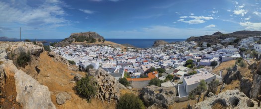 Panorama of the town of Lindos with Acropolis with white buildings by the sea under a blue sky,
