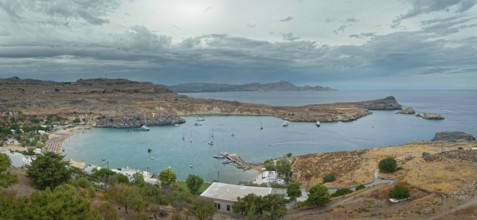 Harbour and coast of Lindos with boats and cloudy sky, Acropolis, Lindos, Rhodes, island, Greece