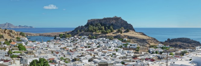 Panoramic view over the coastal landscape of Lindos with Acropolis and hills in the background,