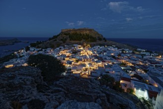 Picturesque Lindos with the ancient Acropolis at dusk with glowing houses and castle in the