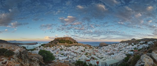 Picturesque Lindos with the ancient Acropolis in the evening light, surrounded by rocks and sea