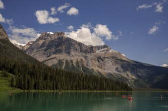 Canoes navigating Emerald Lake surrounded by towering Canadian Rocky Mountains under a clear blue