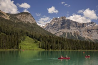 Canoes on the stunning Emerald Lake with the Canadian Rocky Mountains terrain and lush forests