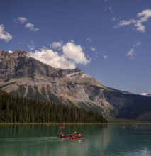 Canoeists on Emerald Lake with the Canadian Rocky Mountains and clouds reflected in the calm water