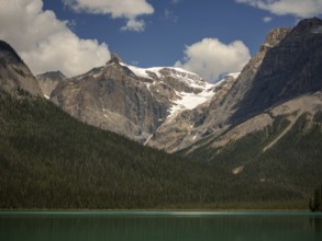 Snowy mountains of the Canadian Rocky Mountains and Emerald Lake with green forest expanse inside