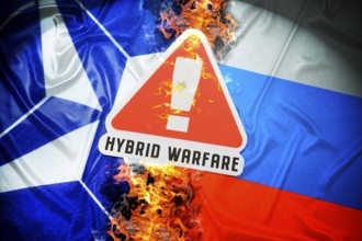 The flags of NATO and Russia with danger sign and inscription Hybrid Warfare, symbolic photo of